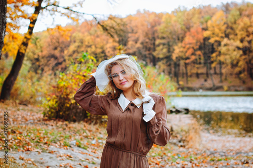 Portrait of young woman in retro dress smiling in autumn park