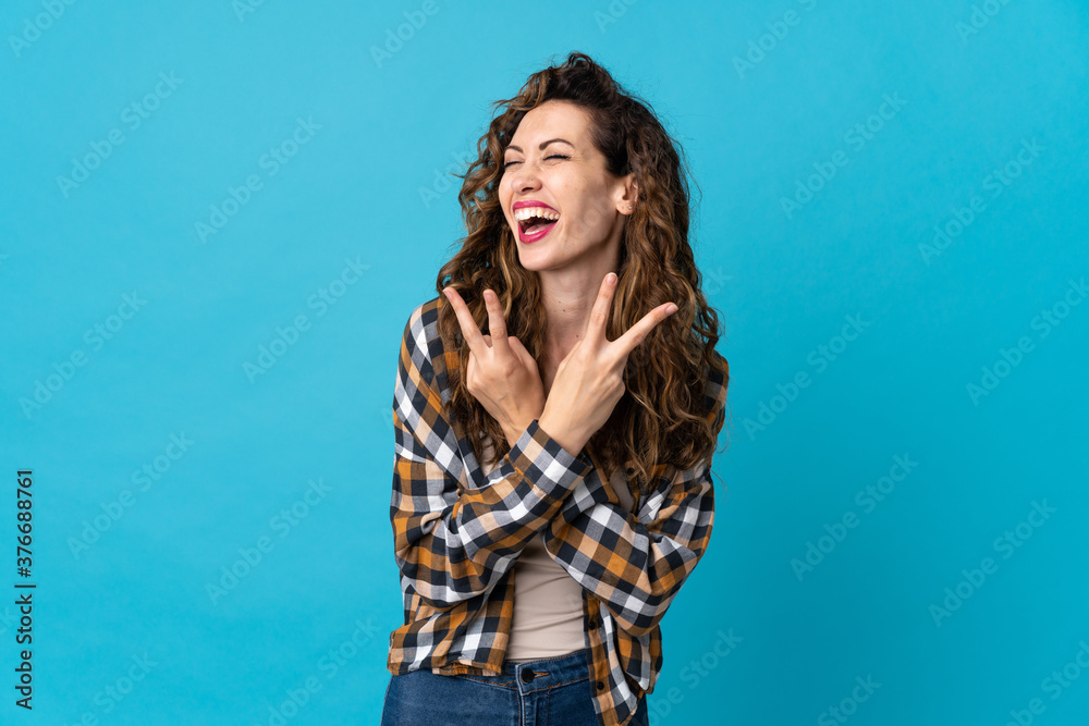 Young caucasian woman isolated on blue background smiling and showing victory sign Young caucasian woman isolated on blue background smiling and showing victory sign