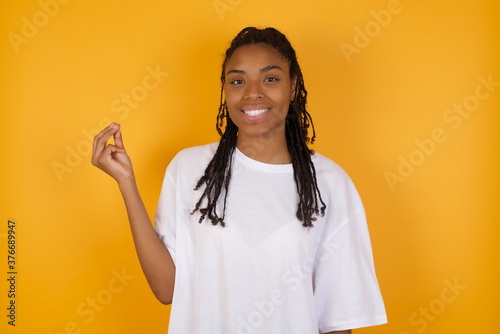 Young dark skinned woman with braids hair wearing casual clothes trendy isolated over yellow background pointing up with hand showing up seven fingers gesture in Chinese sign language QÄ«. © Roquillo