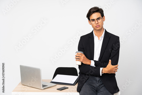Businessman in his office over isolated white background keeping arms crossed © luismolinero