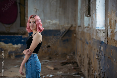 Young funky teenage girl with pink hair in abandoned building.