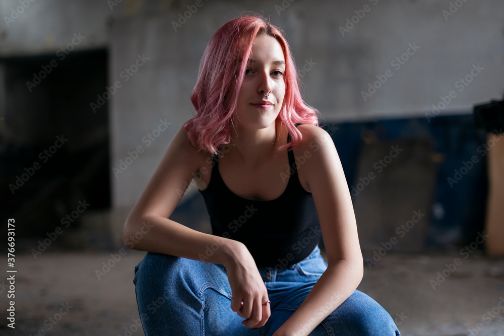 Naklejka premium Young funky teenage girl with pink hair in abandoned building.