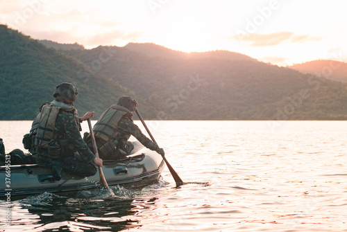Special forces men in camouflage uniforms paddling army kayak. Boat moving across the river in the morning, diversionary mission,copy space. photo