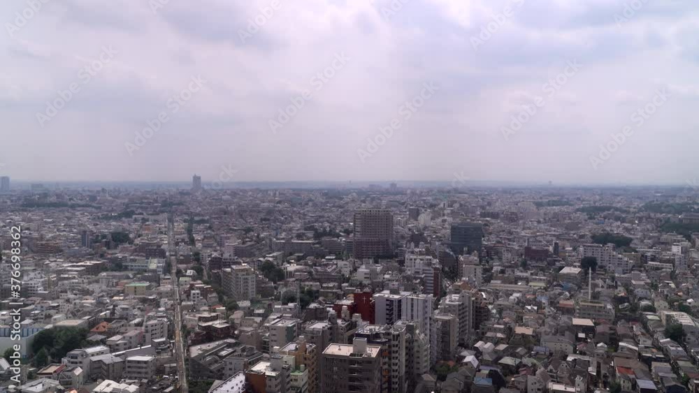 Locked off view over wide Tokyo urban skyline with buildings running into the distance during cloudy day Locked off view over wide Tokyo urban skyline with buildings running into the distance during cloudy day
