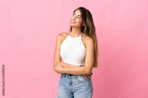 Young caucasian woman isolated on pink background looking to the side and smiling © luismolinero