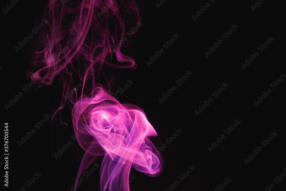 Obraz premium Purple smoke on a black background. Colored smoke. Incense stick smoke illuminated by purple light.