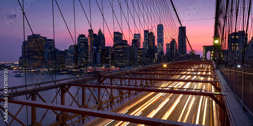Brooklyn Bridge with light trails and view on Lower Manhattan skyscrapers at Dusk. Evening in New York City, NY, USA