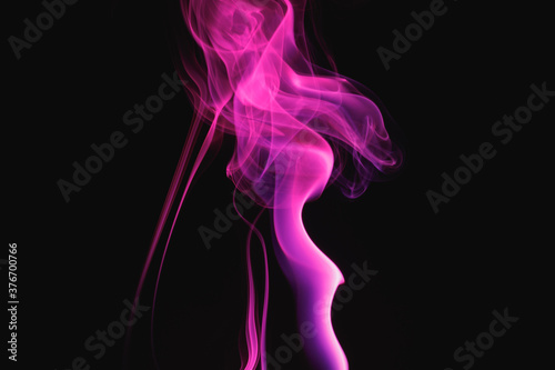 Purple smoke on a black background. Colored smoke. Incense stick smoke illuminated by purple light.
