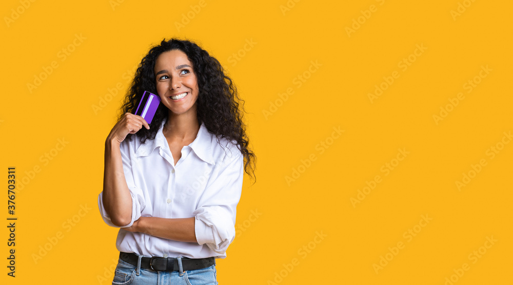 Shopping Time. Dreamy brunette woman holding credit card and looking away Shopping Time. Dreamy brunette woman holding credit card and looking away