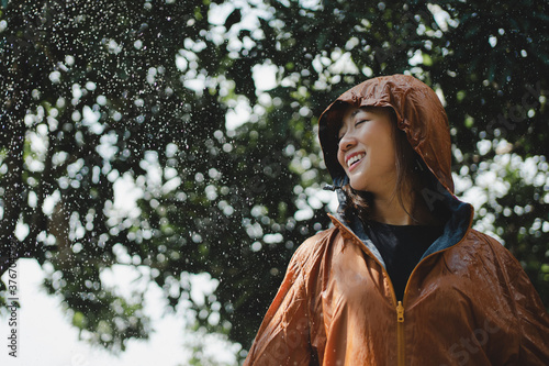 Fotografie Asian woman in an orange raincoat is outdoors