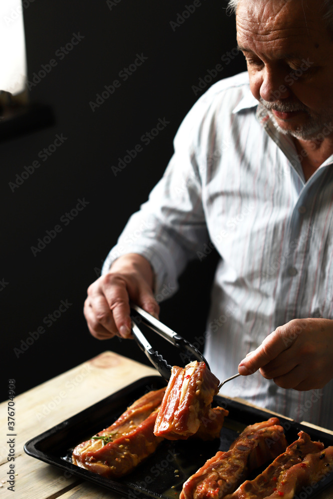 Selective focus. The chef places the marinated pork ribs on a baking sheet. Cooking the ribs.