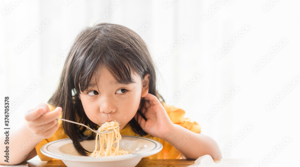 Hungry face and enjoy eating concept.Little asian girl enjoy eating with spaghetti carbonara with cheese on a plate in lunch time at restaurant.kid eating pasta.Delivery food, Delicious face. Hungry face and enjoy eating concept.Little asian girl enjoy eating with spaghetti carbonara with cheese on a plate in lunch time at restaurant.kid eating pasta.Delivery food, Delicious face.