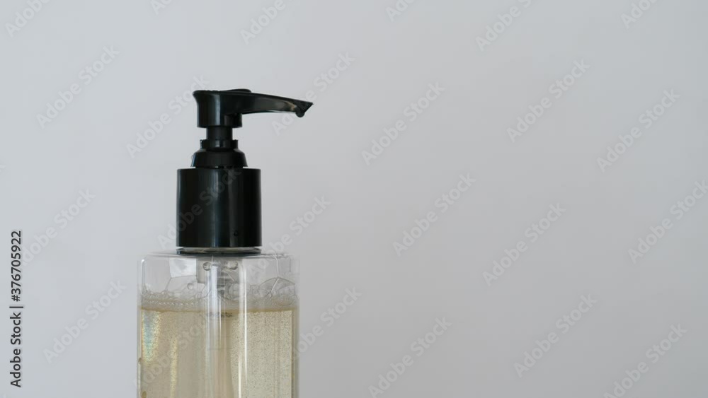 Woman use liquid soap to wash hands, push dispenser bottle pump, cleanser portion spit out to cupped arm. Closeup shot. Personal health care and disease treatment concept