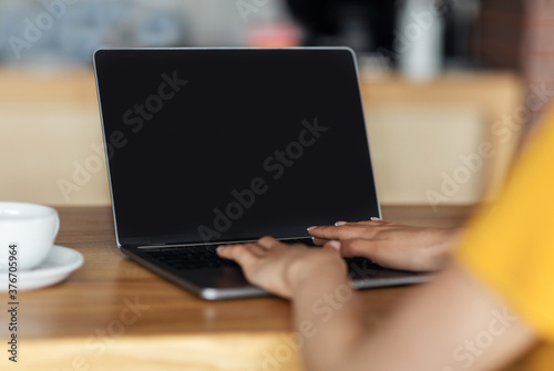 Unrecognizable girl typing on laptop at cafe