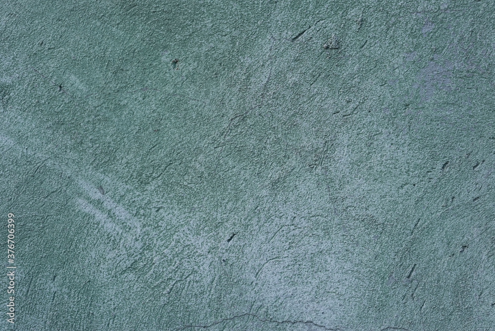 green cracked texture of plaster, with elements of rubbed gray paint. The pastel tone of a textured street wall. Crack in the wall, multiple holes in the old green plaster green cracked texture of plaster, with elements of rubbed gray paint. The pastel tone of a textured street wall. Crack in the wall, multiple holes in the old green plaster