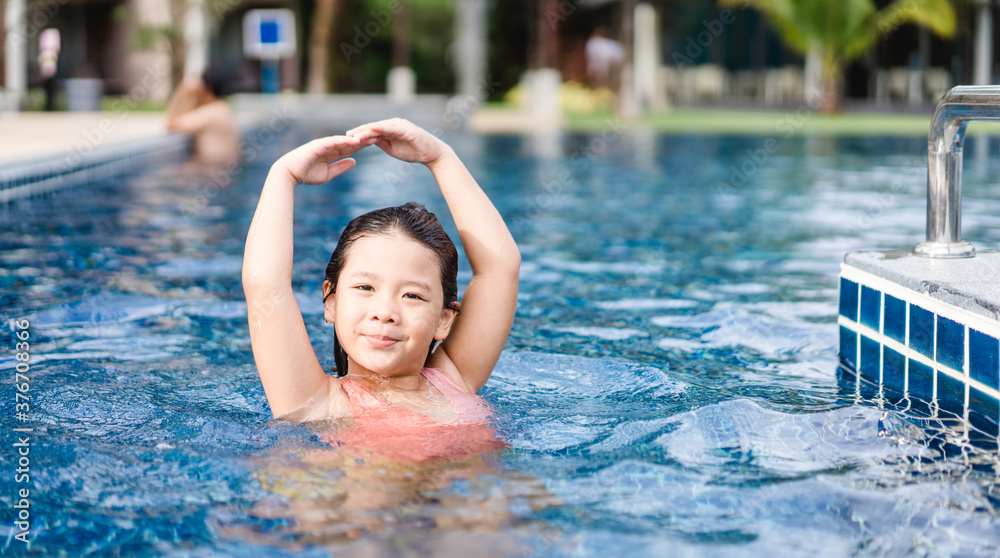 Little girl dancing under the water in the pool.Little ballerinas in ballet outdoor class.Cute little asian girl in swimming pool during a ballet dance class at hotel.