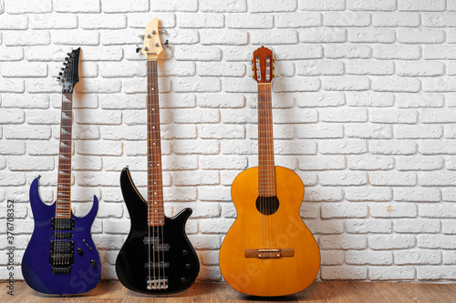 Set of guitars on the floor against white brick wall © fotofabrika