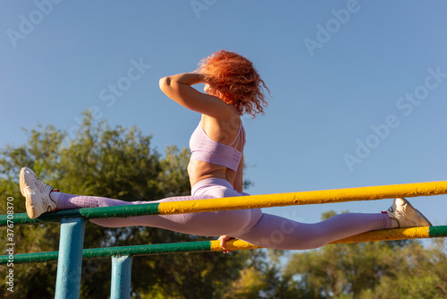 Fototapeta Naklejka Na Ścianę i Meble -  young sportswoman stretches leg muscles before doing sports exercises. Outdoors. Workout