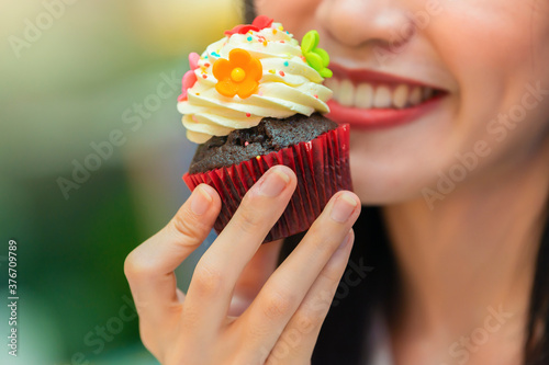 Happy beautiful young woman holding cupcake. Business woman eating unhealthy food snack.