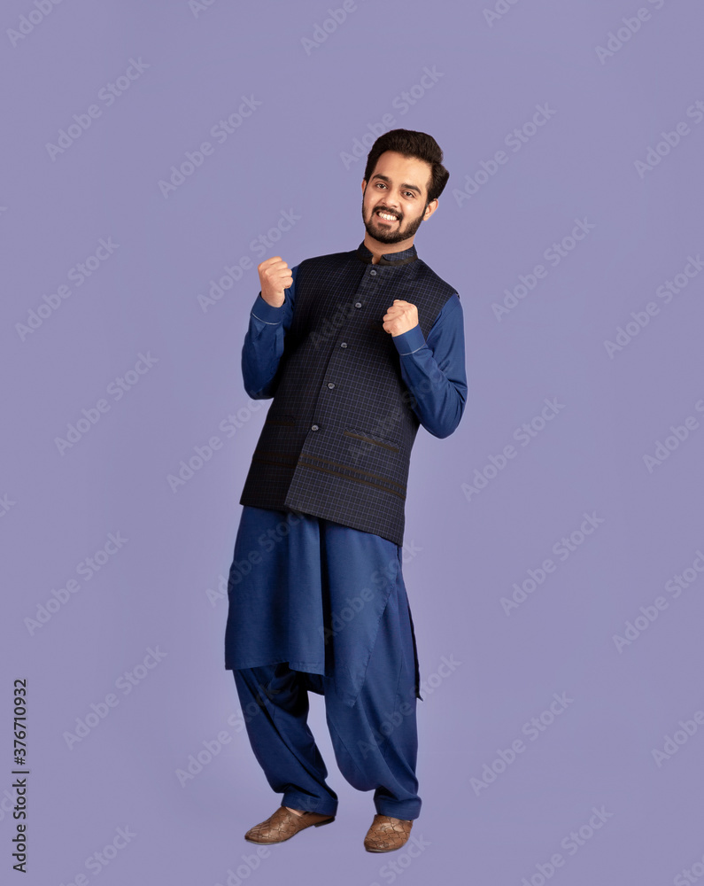 Full length portrait of handsome Indian man in traditional clothes gesturing YES on violet background