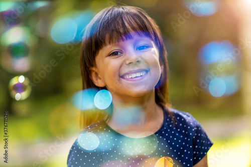 Girl playing with soap bubbles outdoors 