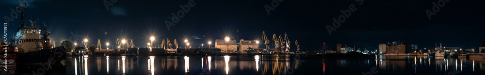 panorama of night port on the river with a ships and cranes