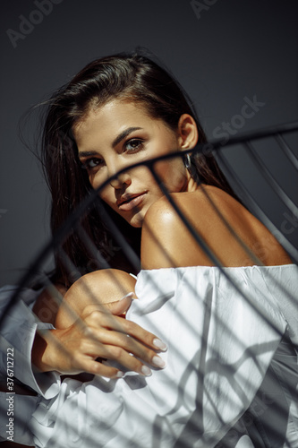sensual beautiful woman lying in sunlight with blinds shadows