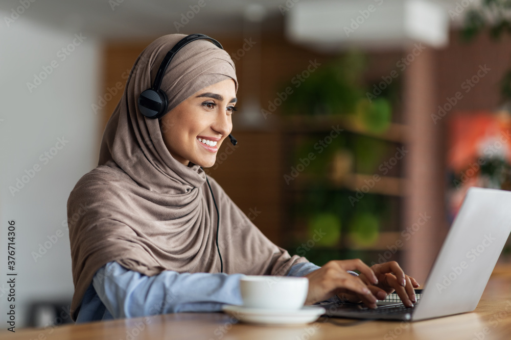 Smiling muslim girl studying online at cafe Smiling muslim girl studying online at cafe