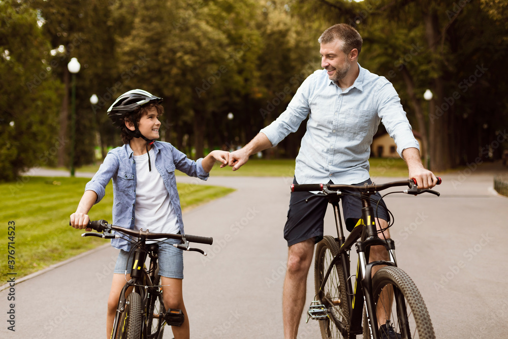 Obraz premium Man giving fist bump to son riding bicycles
