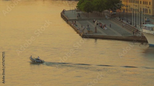 Motorboat Sailing near Evert Taubes Terrass in Stockholm during Golden Hour. Zoom Out. photo