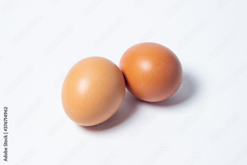 Eggs on a white background. Two chicken eggs lie next to each other Eggs on a white background. Two chicken eggs lie next to each other