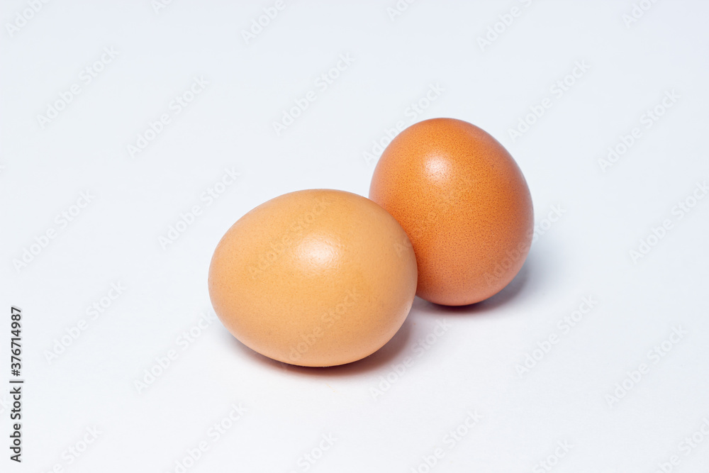 Eggs on a white background. Two chicken eggs lie next to each other Eggs on a white background. Two chicken eggs lie next to each other