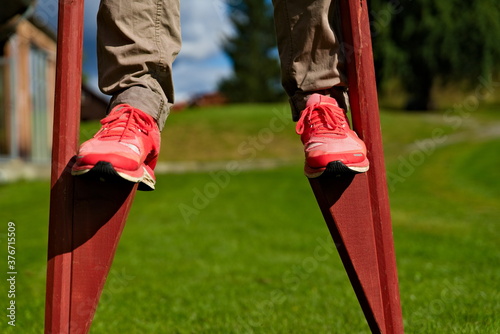 Person walking on wooden stilts on a lawn.