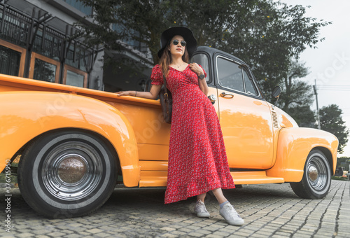 Traveler Asian woman in red dress posing with retro pickup tuck old car on street, Attraction stylish tourist girl on vacation trips, Lifestyle Asia people with vintage classic american car © day2505