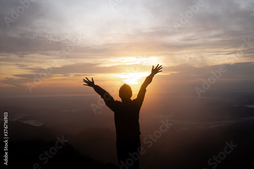 Silhouette women standing on cliff and see sun up.She is raise hand up and enjoying fresh air.She enjoying free happiness in beautiful Thailand landscape. photo concept active and nature background.