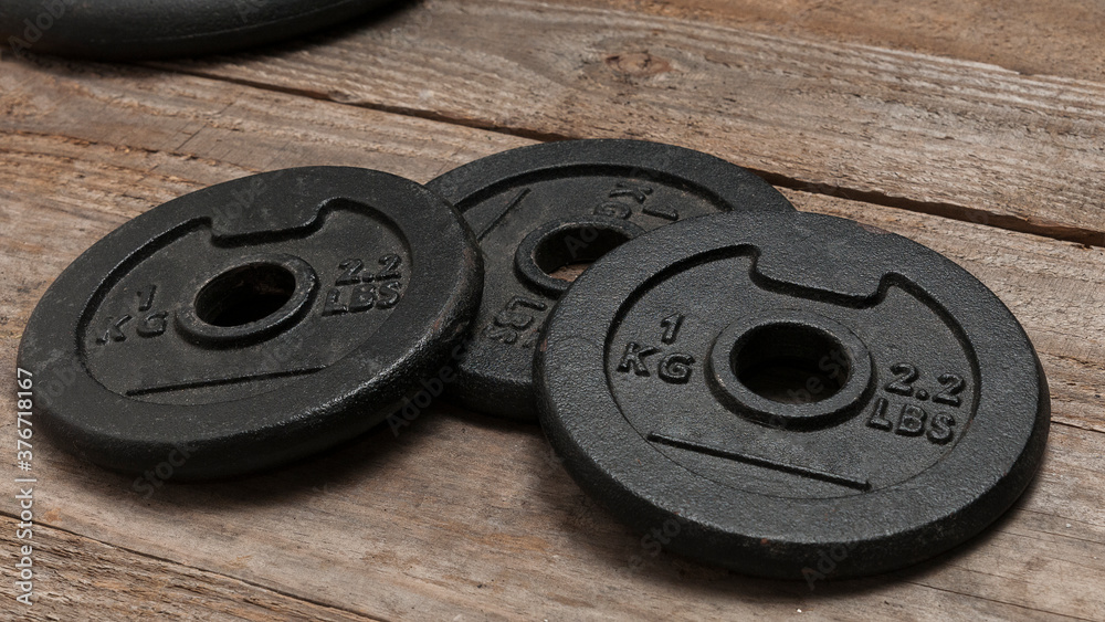 Three dumbbell discs for weight lifting on wooden floor Three dumbbell discs for weight lifting on wooden floor