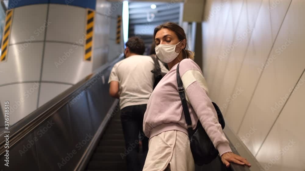 Young woman wearing a protective mask against the virus climbing escalators on public transport Young woman wearing a protective mask against the virus climbing escalators on public transport