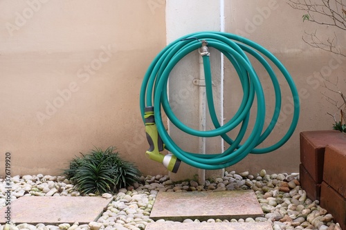 watering hose hanging on faucet in garden
