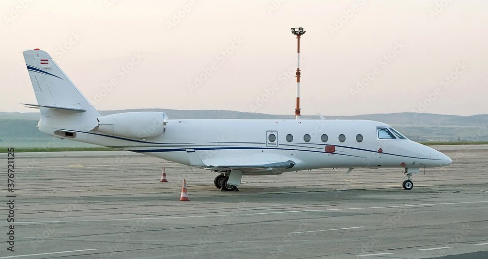 Side view of white business jet with turbofan engines at the airport. Modern technology in fast transportation, business travel and tourism, aviation concept. Side view of white business jet with turbofan engines at the airport. Modern technology in fast transportation, business travel and tourism, aviation concept.