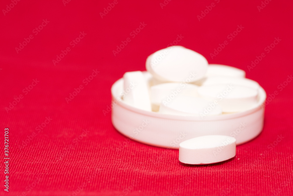 handful of white pills lies in the lid on a red handful of white pills lies in the lid on a red