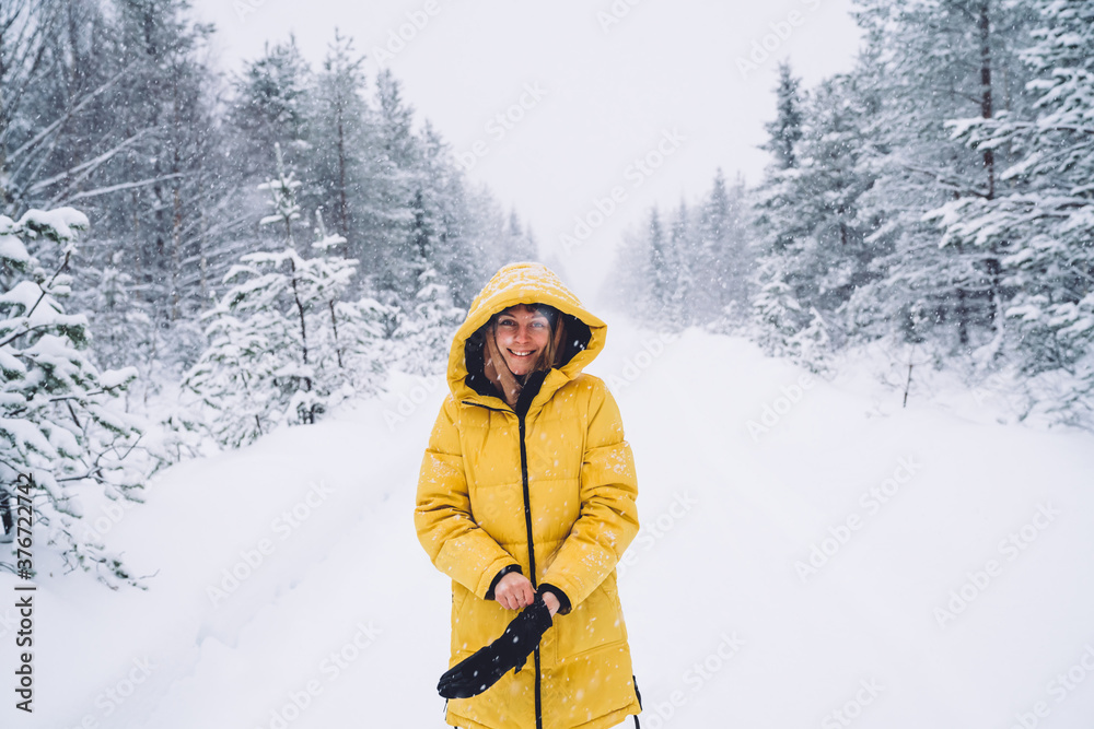 Cheerful caucasian woman in winter coat feeling warm on white snowy nature environment in wood, happy female explorer enjoying north destination on holiday vacations