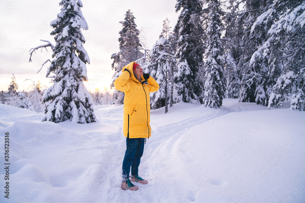 Happy caucasian woman traveler standing in winter forest enjoying view and snow, female tourist explore Riisitunturi national park destination