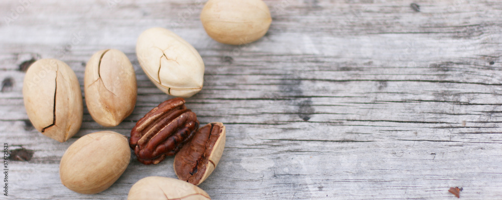 Pecan Nuts on wooden background, top view with copyspace. Close up veiw of nuts. Banner size with copy space. 