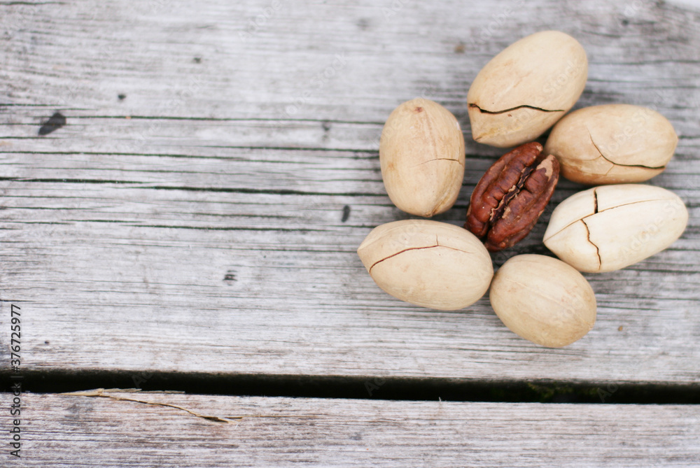 Obraz premium Pecan Nuts on wooden background, top view with copyspace. Close up veiw of nuts.