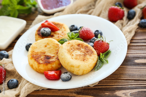 Sweet cheese pancakes with berries and mint leafs on wooden table