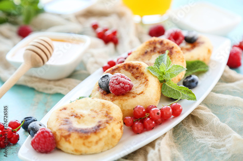 Sweet cheese pancakes with berries and mint leafs on blue background