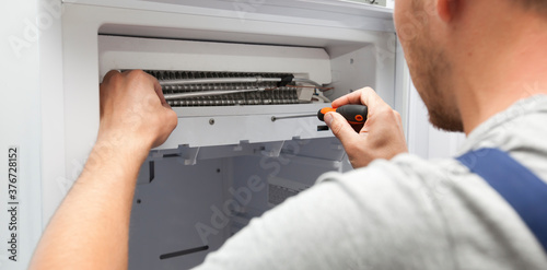 The repairer is fixing the freezer at home