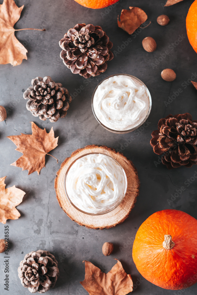 Fototapeta premium Autumn background with natural pine cones, pumpkins, dried leaves and pumpkin latte on dark grey stone top, top view, copy space. Fall, Thanksgiving background, cozy flat lay