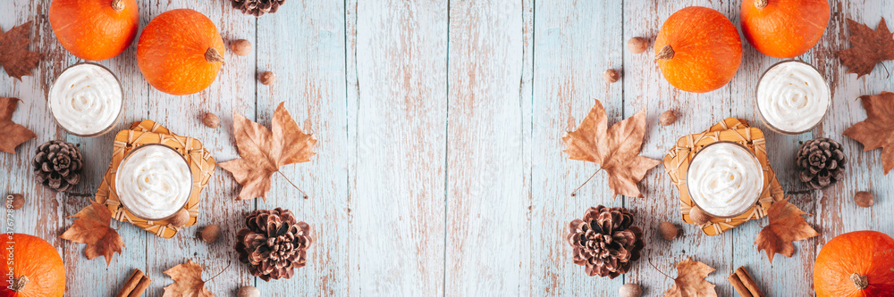 Autumn border banner with natural pine cones, pumpkins, dried leaves and pumpkin latte on worn wooden table, top view, copy space. Fall, Thanksgiving background web banner, cozy flat lay
