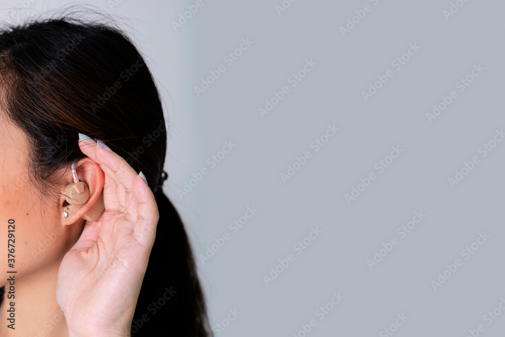 Young woman with hearing aid on Gray isolated background Young woman with hearing aid on Gray isolated background